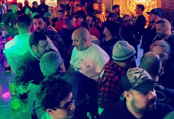 Crowded Bacon Bear Bar in Barcelona. Gay bar scene with many men, drinks on the bar, and a lively atmosphere. Gay travel advice.