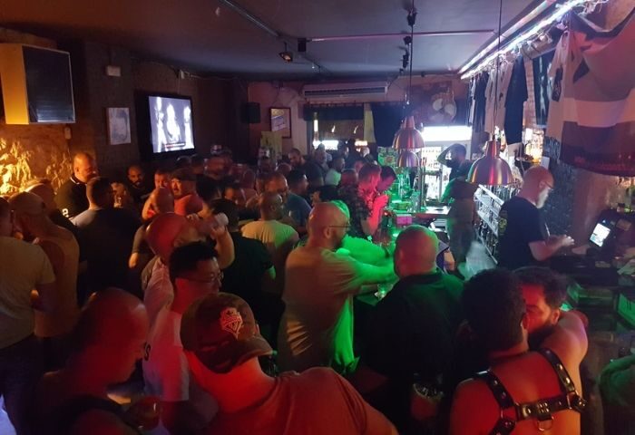 Busy Bacon Bear Bar in Barcelona. A lively gay bar scene with a crowd of men, bar area, and vibrant lighting for gay travel advice.