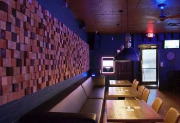 Interior of Badlands Las Vegas, a gay bar. Wood block wall art, tables, and a long sofa. Blue lighting. Gay travel advice.