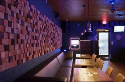 Interior of Badlands Las Vegas, a gay bar. Wood block wall art, tables, and a long sofa. Blue lighting. Gay travel advice.