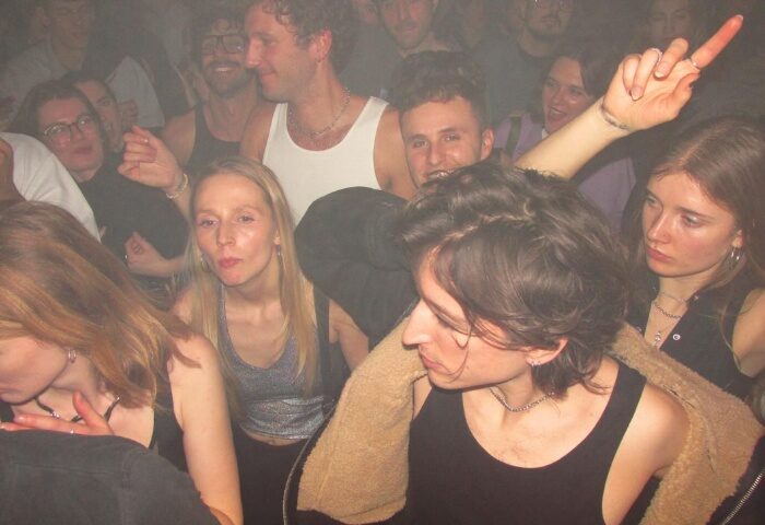 Baggen Copenhagen club scene: diverse crowd of young adults dancing in a smoky, dark space. Gay travel nightlife in Denmark.
