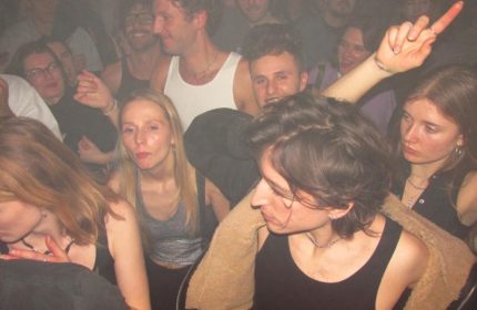 Baggen Copenhagen club scene: diverse crowd of young adults dancing in a smoky, dark space. Gay travel nightlife in Denmark.