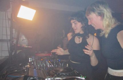 Baggen Copenhagen: Two women DJs at a gay club, smiling and working the turntables. Nightlife scene, music, and travel advice.