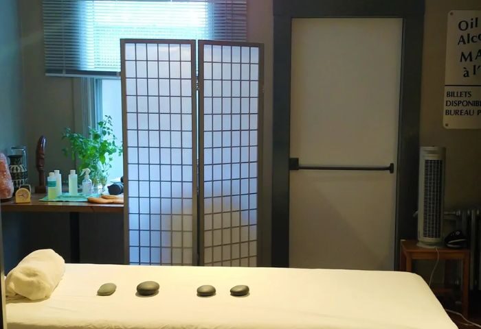 Interior of Bain Colonial gay spa in Montreal. Massage table with stones, screen, and products on a table. Relaxing bathhouse ambiance.