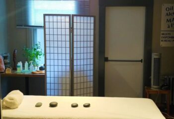 Interior of Bain Colonial gay spa in Montreal. Massage table with stones, screen, and products on a table. Relaxing bathhouse ambiance.