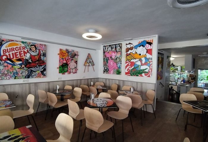 Interior of Baloo Bar Lounge, a gay bar in Torremolinos, Spain. Tables and chairs are arranged under pop art featuring Donald Duck.