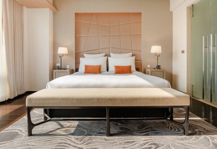 VIE Hotel Bangkok room. Modern interior with king bed, orange pillows, and bench. Gay-friendly hotel on Bangkok Number One Gay Hotels List.