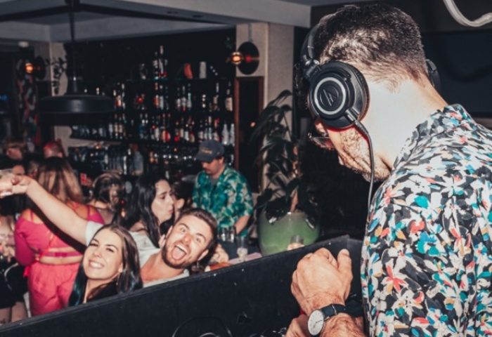 Gay nightlife at Newtown's Bank Hotel: DJ with headphones plays music for a happy crowd at the bar. Gay travel advice.