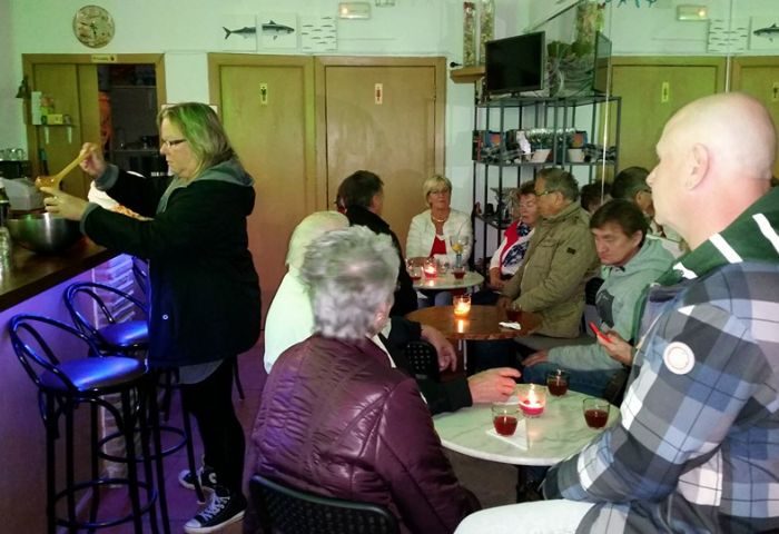 Inside Babel Gay Bar in Torremolinos, Spain. People sit at tables with drinks, while a woman mixes a drink at the bar. Nightlife scene.