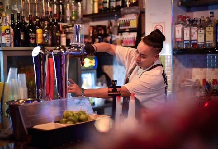Bartender at Divinity Gay Bar in Gran Canaria. Drinks being prepared, limes, and a fully stocked bar. Gay travel in Gran Canaria.