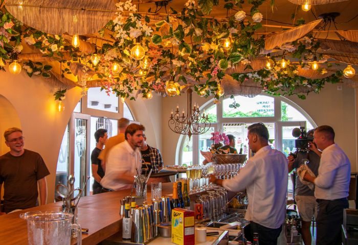 Havana gay bar in Torremolinos. Bartender at work in a stylish bar with floral decor and soft lighting. Gay travel destination.