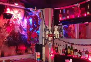 Gran Canaria gay cruise club bar interior. Fetish decor, chains, devil art, and liquor bottles. Hell themed gay bar in Gran Canaria.