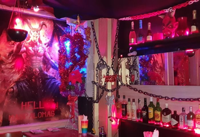 Gran Canaria gay cruise club bar interior. Fetish decor, chains, devil art, and liquor bottles. Hell themed gay bar in Gran Canaria.