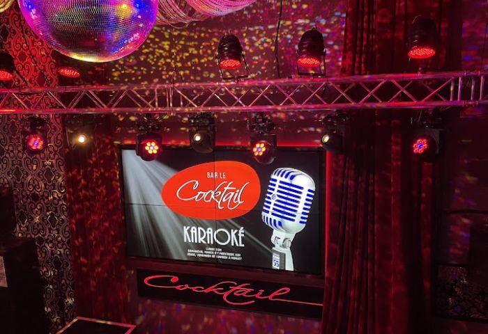 Gay party at Bar Le Cocktail in Montreal. Disco ball, stage lights, and karaoke screen with microphone. Gay travel advice.