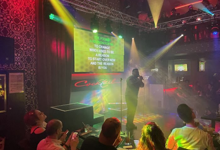 Montreal gay party at Bar Le Cocktail. Karaoke night with a singer on stage and the lyrics on a screen. Crowd enjoying the show.