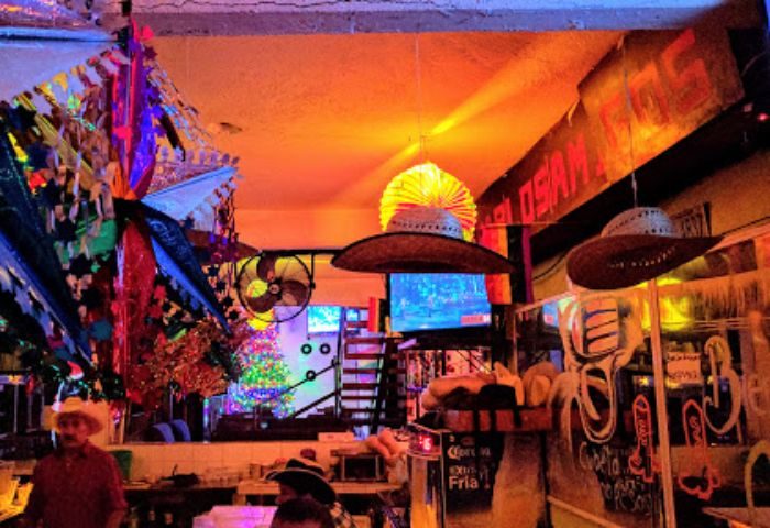 Interior of Bar Los Amigos, a gay bar in Puerto Vallarta. Festive decor, hats, and a lively atmosphere. Gay travel destination.
