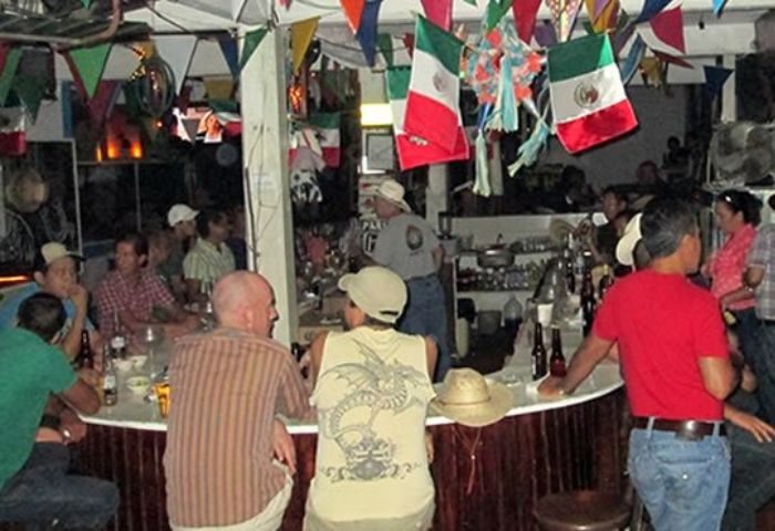 Los Amigos gay bar in Puerto Vallarta. Interior view of the bar with patrons, Mexican flags, and festive decorations. Gay travel.