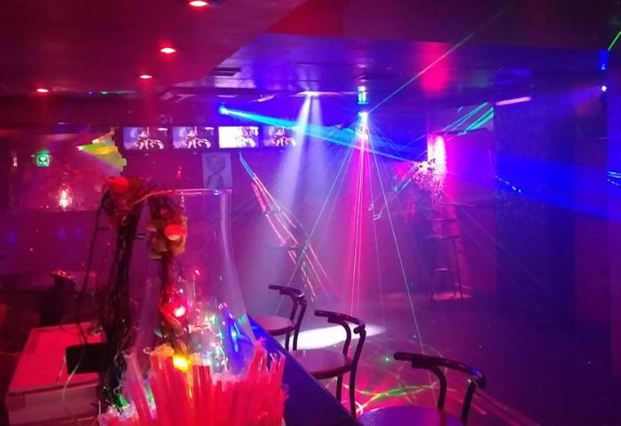 Inside Mercury Bar, Benidorm's gay party scene. Drinks, bar stools, and laser lights create a vibrant atmosphere for gay men's travel.