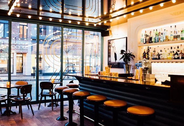 Bar Renard in Montreal: Stylish interior view of the gay-friendly bar with stools, bottles, and a large window to the street.