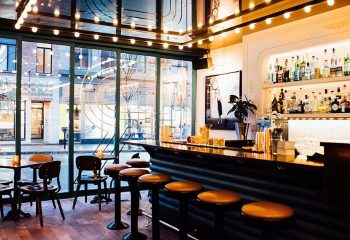 Bar Renard in Montreal: Stylish interior view of the gay-friendly bar with stools, bottles, and a large window to the street.