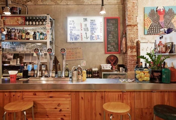 Bar Rufián's interior, a gay bar in Barcelona. Rustic decor, bar stools, drinks, and menus. A popular spot for gay men's travel.