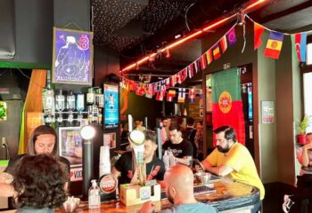 Bar TR3S in Lisbon, Portugal. Gay bar scene with bartender, patrons, flags, and decor. Gay travel advice for Lisbon nightlife.