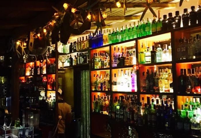 Baranoa Gay Bar in Madrid. Shelves stocked with liquor bottles, lit by string lights. A popular gay bar destination in Madrid, Spain.