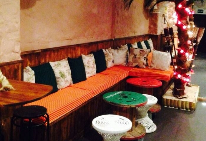 Baranoa Gay Bar in Madrid: Cozy seating area with colorful pillows and unique tables. A welcoming space for gay travelers.