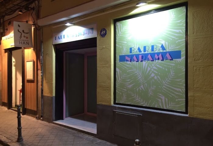 Barbanarama Gay Bar entrance in Madrid. Night scene of the bar's exterior with its sign and tropical-themed decoration. Gay travel advice.