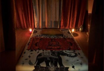 Gay massage in Barcelona: Massage table with elephant and buddha prints. Candles and curtains create a relaxing atmosphere.