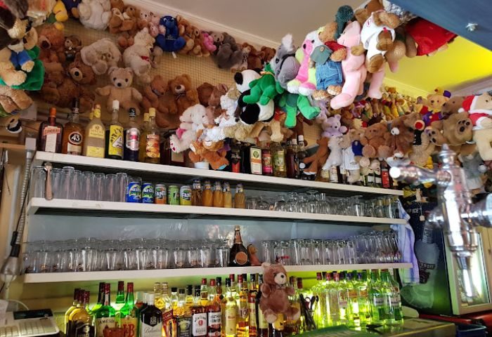 Bärenhöhle (Bear Cave) Gay Bar in Gran Canaria. Shelves of liquor bottles and glasses, teddy bears hanging from the ceiling and walls.