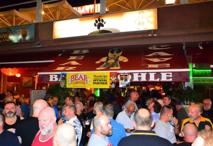Bärenhöhle Bear Cave gay bar in Gran Canaria. A crowd of gay men gather outside the bar, which has a bear theme. Nightlife scene.