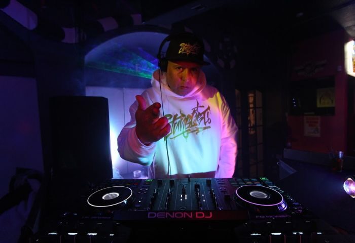 DJ at Bart Lounge, a gay bar. Man with headphones and hoodie stands behind a DJ console. Nightlife scene, perfect for gay travel.