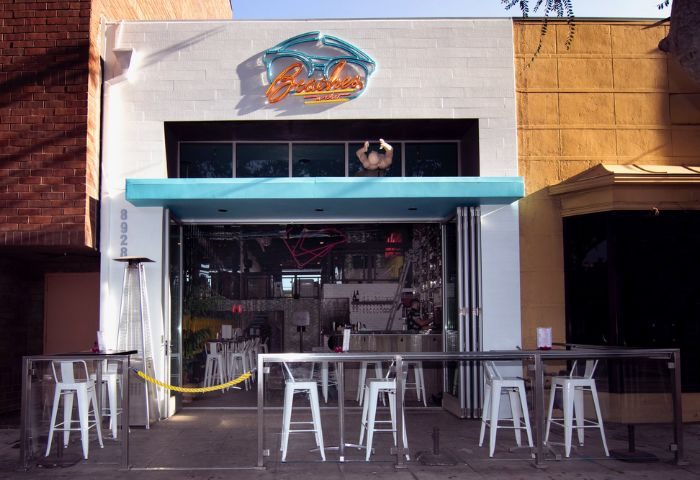 Beaches WeHo location: Exterior view of the gay bar Beaches in West Hollywood, California. Neon sign, open facade, and outdoor seating.