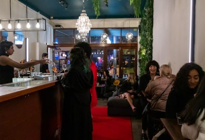 Beans Bar Melbourne: Interior view of the gay bar. Bartender serving drinks at the counter. People socializing. Nightlife scene.