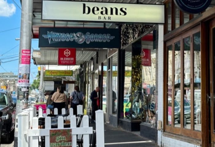 Beans Bar Melbourne street view. Outdoor seating area with white picket fence. A gay-friendly bar, part of Melbourne's scene.