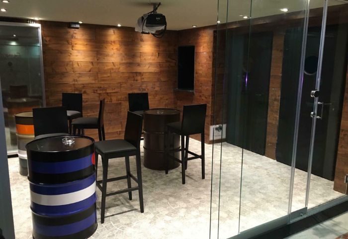 Bears Bar Sitges interior. Tables made from barrels, black chairs, wood paneled walls, and glass enclosed room. Gay bar travel advice.