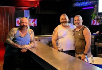 Three gay men at Bears Bar, Sitges. The man on the left has tattoos. Gay travel advice. Sitges gay bar scene.