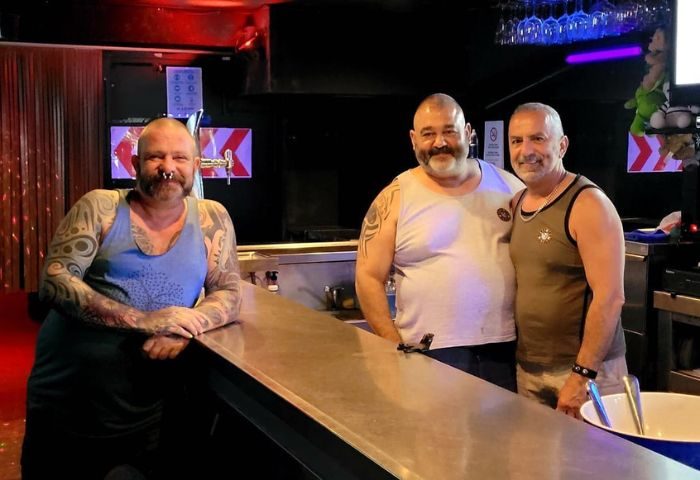 Three gay men at Bears Bar, Sitges. The man on the left has tattoos. Gay travel advice. Sitges gay bar scene.