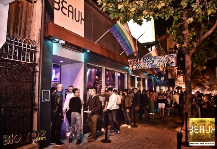 Beaux Gay Bar in San Francisco. A line of gay men wait outside the popular bar, rainbow flags flying above. Nightlife in the Castro District.