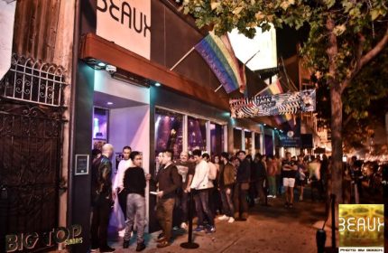 Beaux Gay Bar in San Francisco. A line of gay men wait outside the popular bar, rainbow flags flying above. Nightlife in the Castro District.