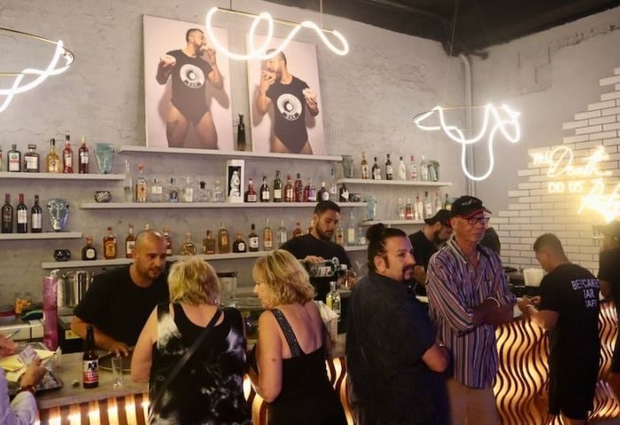 Inside Beefcakes Gay Bar in Puerto Vallarta, Mexico. Bartenders and patrons at the bar. Neon lights and beefcake art. Gay travel.