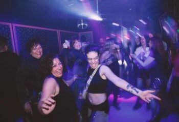 People dancing at Believe gay club in Barcelona. Nightlife scene with disco ball, lights, and happy crowd. Gay travel in Spain.