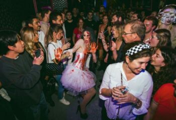 Crowded scene at Believe Club, a gay club in Barcelona. A person in a bloody Halloween costume is surrounded by partygoers.