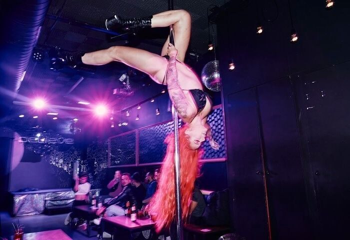 Drag queen pole dancing at Believe, a gay club in Barcelona. Nightlife scene with people watching the performance. Gay travel advice.