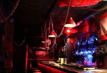 Interior of Berlin Dark gay cruise club in Barcelona, Spain. Themed bar with chains, dim red lighting, and a fetish-friendly atmosphere.