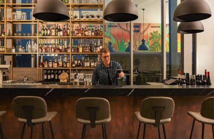 Hotel Indigo Berlin East Side Gallery bar with bartender holding drink. Great reviews, popular cheap hotel for gay men travel advice.