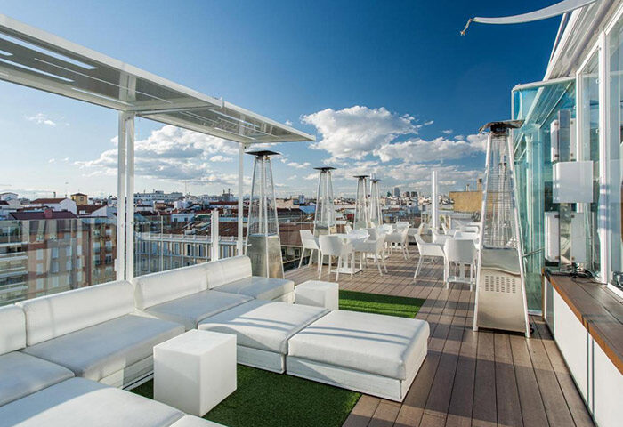 Room Mate Oscar: Madrid gay hotel rooftop pool with city view. Lounge seating, tables, and heaters on the terrace. Best gayborhood spot.