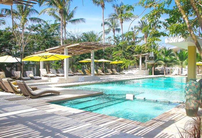 Koh Phangan Summer Luxury Beach Resort pool view. Upscale beachfront gay hotel with lounge chairs and yellow umbrellas.