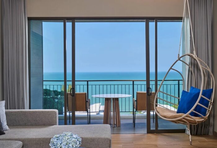 Renaissance Pattaya Resort & Spa room with ocean view. Balcony with table, chairs, and hanging chair. Best beach holiday near Bangkok.